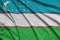 Uzbekistan flag is depicted on a sports cloth fabric with many folds. Sport team banner