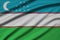 Uzbekistan flag is depicted on a sports cloth fabric with many folds. Sport team banner