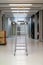 V shaped open ladder standing on a laboratory hallway corridor illuminated by neon lights shallow depth of field front view