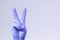 V sign is showed by right man hand in a purple medical glove on a white background. Victory over a virus