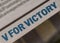 V for Victory tagline in newspaper with blue and bold letters