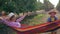 Vacation in apple garden, happy child swings his mother in a hammock between rows of trees
