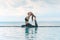 Vacation of Attractive Asian woman relaxing in yoga king pigeon pose on the pool above the beach with beautiful sea in Tropical is
