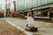 Vacation with children. A boy sits on a suitcase on the platform at the train station. A train is waiting, it is boring for him to
