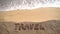 Vacation concept on the beach. Word Travel written on the sand near the sea. Copy space