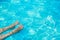 Vacation concept. Female legs with white nails in blue water swimming pool. Tropical relaxation