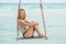 Vacation concept. Happy young woman sitting on swing enjoying se