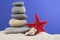 Vacation concept. Red starfish, seashell with nice stones put on each other against nice blue background
