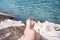 Vacation Concept. Tanning on the Beach. Woman`s Bare Feet over Sea background