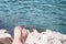 Vacation Concept. Tanning on the Beach. Woman`s Bare Feet over Sea background