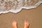 Vacation concept, women foot near sea foam at gold sand