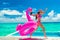 Vacation fun woman in bikini with funny inflatable pink flamingo pool float running of joy jumping by infinity swimming