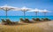 Vacation holidays - four beach lounge chairs under tent on beach of Mediterranean with a yacht on the background.