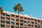 Vacation rental apartment building balconies and palm tree on sunny day