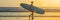 Vacation Silhouette Of A Surfer Carrying His Surf Board Home At Sunset With Copy Space BANNER, long format