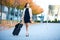 Vacation. Smiling female passenger proceeding to exit gate pulling suitcase through airport concourse