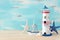 Vacation and summer concept with vintage boat, starfish, lighthouse and seashells over wooden table or shelf infront of pastel