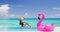 Vacation summer fun woman sunbathing with inflatable pink flamingo pool float by infinity swimming pool. Luxury travel