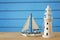 Vacation and summer image with lighthouse and boat over blue wooden planks background.