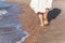 vacation travel - woman leg closeup walking on white sand relaxing in beach cover-up pareo beachwear. and tanned legs.