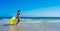 Vacation woman in bikini with yellow float walking along the seashore. Holiday lifestyle scene