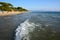 Vacationers sunbathe on the beach near the sea. Waves roll onto the shore