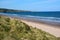 Vacationers walk along the wide sea coast with a beach. A view from afar