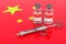 Vaccination in China concept. Vaccine bottles with syringe on the Chinese flag, 3D rendering