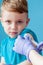 Vaccination concept. Female doctor vaccinating cute little boy on blue background, closeup