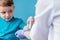 Vaccination concept. Female doctor vaccinating cute little boy on blue background, closeup