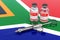 Vaccination in South Africa concept. Vaccine bottles with syringe on the South African flag, 3D rendering