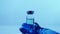 Vaccine against COVID-19 concept. Lab scientist holding sterile vial with blue antivirus. Searching for a cure from respiratory