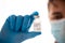 Vaccine bottle in male hand close up, doctor in medical mask. Concept of vaccination, Covid-19 coronavirus diagnostic, cure for