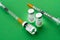 Vaccine Comirnaty vials with syringes on green background