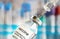 Vaccine glass bottle with syringe injected, blurred vials background