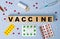 Vaccine word on wooden cubes on the background of syringe, tablets, ampoules. Medicine concept