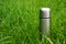 Vacuum insulated steel thermos bottle in the green grass at summer picnic