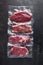 Vacuum packed organic raw beef alternative cuts: top blade, rump, picanha, chuck roll steaks, over black textured background, top