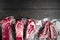 Vacuum packed organic raw beef classic cuts, tomahawk, t bone, club steak, rib eye and tenderloin cuts, on black wooden table