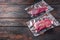 Vacuum packed Rump Steak from organic  beef on dark old wooden background, side view with space for text