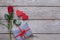 Valentine background with red rose flower, paper hearts and present box on rustic wood