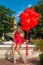 Valentine Beautiful girl with red balloons laugh, in the park. Beautiful happy young woman. Birthday party.