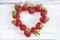 Valentine card: Strawberries heart on white paint wooden background