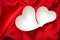 Valentine day concept with two heart empty shaped white bowls on red silk/ satin background with waves and ripples in the silky