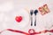 Valentine day concept, wineglass and red ribbon and utensil put in heart on white wooden table background.