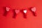 Valentine Day holiday. Four cute little small clothespins with pattern hearts on red crimson background with copyspace. Romantic