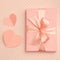 Valentine day idea composition: pink or coral gift box with ribbon and small hearts on living coral background. Top view. Flat lay