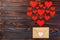 Valentine day love letter. Envelope from craft paper with red hearts heap spread on white wood background. Lover`s holiday confes