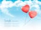 Valentine heart-shaped baloons in a blue sky with clouds.