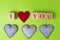 Valentine hearts of jeans and rustic alphabet blocks that spell out I Love You on greenery background. Top view. Copy